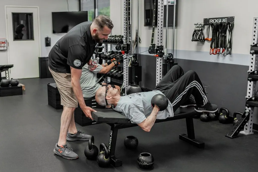 A STRONG coach spotting a member on a bench press