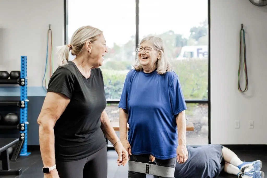 Two STRONG members laughing together between exercises