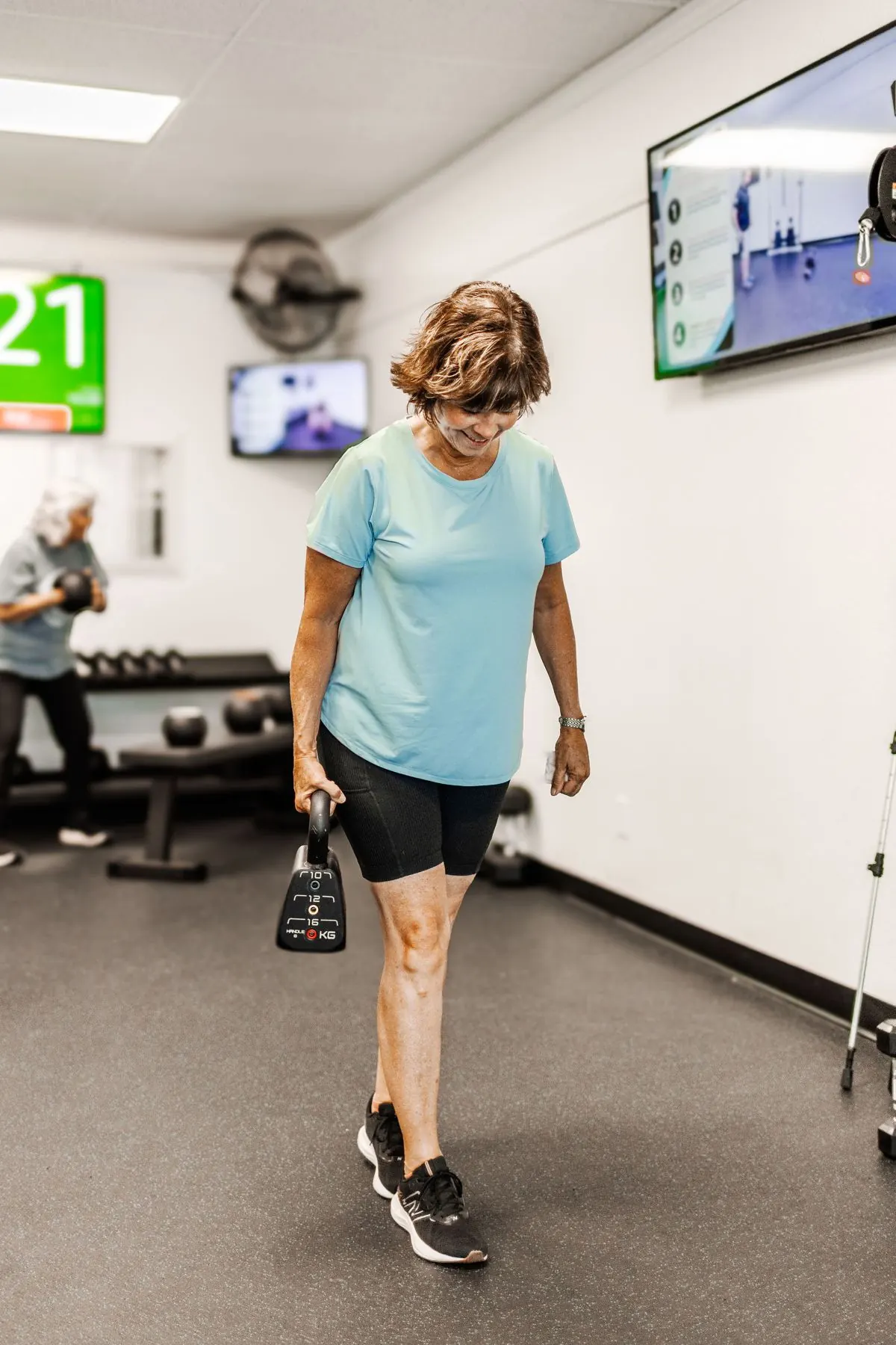 A STRONG member carrying a kettlebell across the gym floor