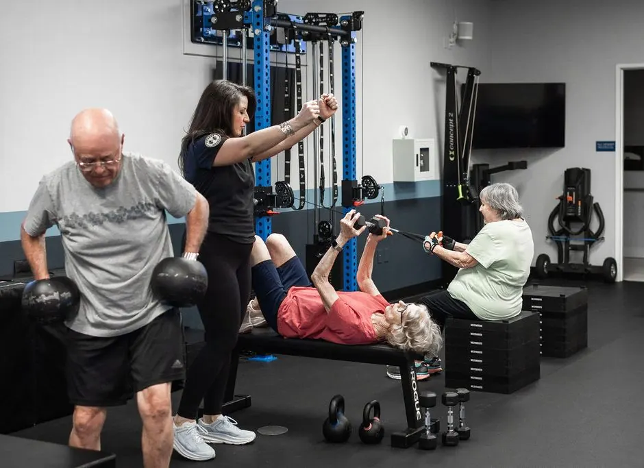A coach guiding three members, each on their own program
